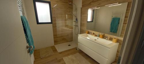 een badkamer met een wastafel en een douche met een spiegel bij Agréable villa neuve orientée vers la nature et le couché de soleil! in Le Verdon-sur-Mer
