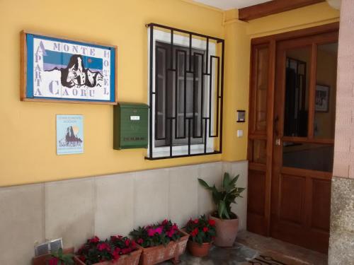 a front door of a building with flowers and a sign at Apartahotel Montecaoru in Arenas de Cabrales