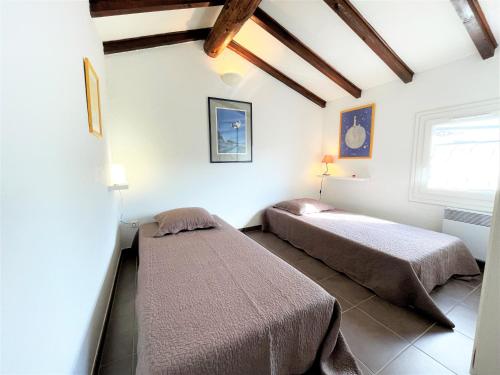 Cette chambre blanche dispose de 2 lits et de plafonds en bois. dans l'établissement Appartement A Stagnola PORTICCIO, à Porticcio