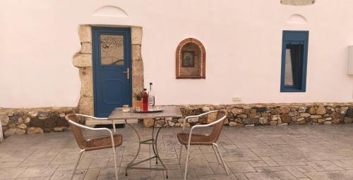 a table with two chairs and a blue door at Grandpa's place in Lagoúdi Zía