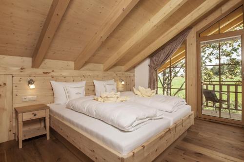a large bed in a wooden room with a window at Bayern Chalets bei Salzburg und Berchtesgaden mit Whirlpool und Sauna in Ainring