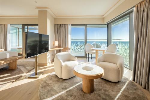 a living room with a large television and chairs and tables at EVOLUTION Cascais-Estoril Hotel in Estoril