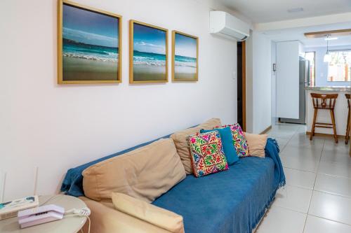 ein Wohnzimmer mit einem blauen Sofa und einigen Gemälden in der Unterkunft Village pé na areia na Praia da Espera - Itacimirim in Itacimirim