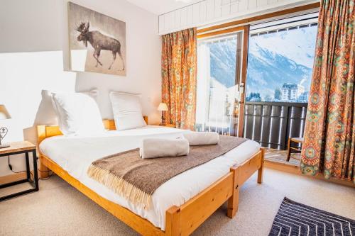 une chambre avec un lit et une grande fenêtre dans l'établissement Le Savoy 2 - Pied des pistes - Centre, à Chamonix-Mont-Blanc