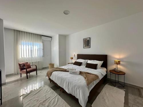 a bedroom with a large bed and a chair at Saf-Saf Apartment 2 in La Marsa