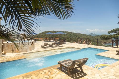 uma piscina com um banco, uma mesa e cadeiras em Pousada La Dolce Vita em Búzios