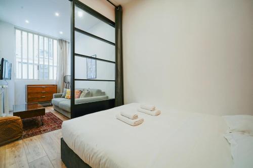 1 dormitorio con 1 cama blanca y sala de estar en Parisuites Central Canal Saint Martin Design & Luxe & Cosy, en París