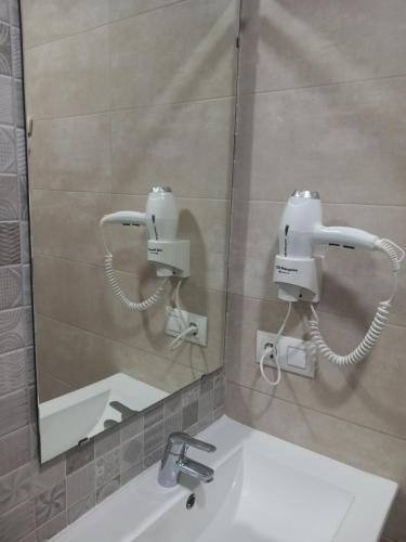 baño con espejo y lavabo blanco en Hostal Restaurante La Ilusion, en El Palmar
