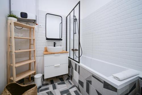 une salle de bain avec un lavabo et une baignoire dans l'établissement Parisuites Central Canal Saint Martin Design & Luxe & Cosy, à Paris