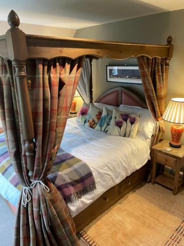 een slaapkamer met een hemelbed en gordijnen bij Clachan Garden B&B in Garve