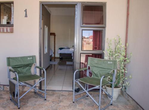 Duas cadeiras sentadas num alpendre com um quarto em OceanLife Accommodation Luderitz em Lüderitz