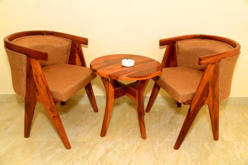 dwa krzesła i drewniany stół z kubkiem w obiekcie Ranthambhore Tiger Niwas w mieście Sawai Madhopur