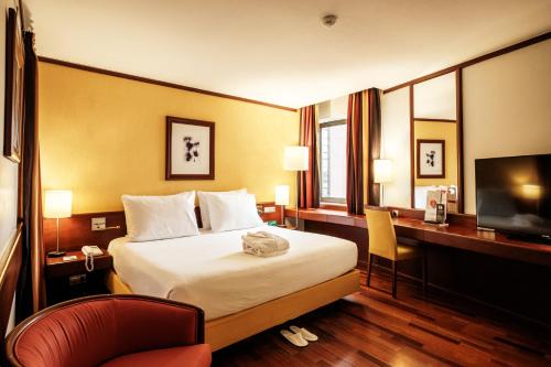 ein Hotelzimmer mit einem Bett, einem Schreibtisch und einem TV in der Unterkunft Holiday Inn Lisbon-Continental, an IHG Hotel in Lissabon