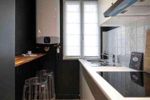 een keuken met een wastafel en een fornuis top oven bij Appartement cosy cœur de Neuilly-sur-Seine in Neuilly-sur-Seine