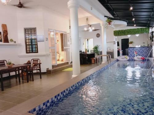 una piscina in un edificio con una sala da pranzo e un tavolo di Comfortable Private Swimming Pool Homestay Melaka 20 Pax 5R3B a Malacca