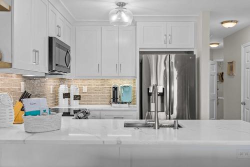 a kitchen with white cabinets and a stainless steel refrigerator at Villa Capriani Condo with Direct Beach Access! in North Topsail Beach