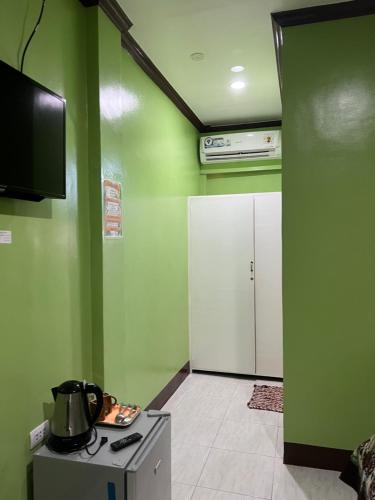 a kitchen with green walls and a stove and a tv at Stella'z guesthouse in Siquijor