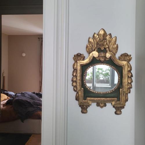 a mirror hanging on a wall next to a bed at La Chambre du 21 in Trouville-sur-Mer