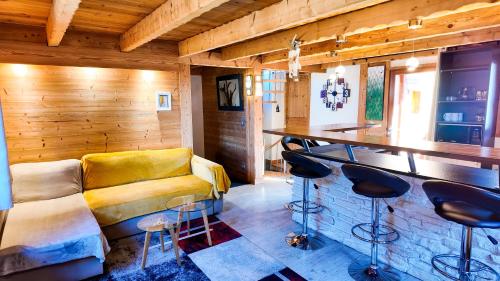 a living room with a yellow couch and a bar at Le Grenier 1821 - Mini chalet - Centre village - AravisTour in Saint-Jean-de-Sixt