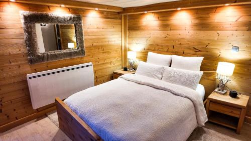 a bedroom with a wooden wall with a bed and a mirror at Le Grenier 1821 - Mini chalet - Centre village - AravisTour in Saint-Jean-de-Sixt