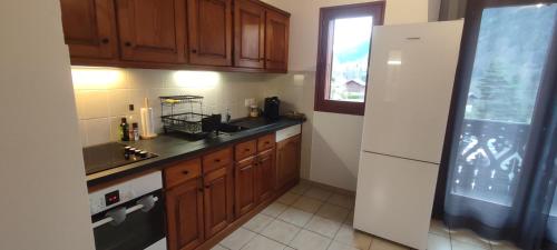 a kitchen with wooden cabinets and a white refrigerator at La Chamade in Le Biot