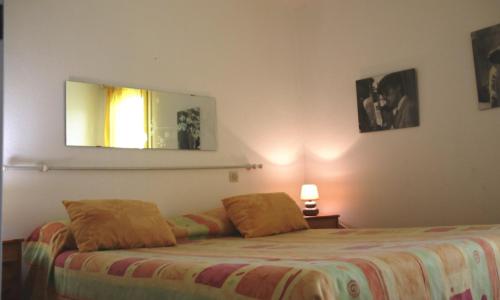 une chambre avec un lit et un miroir au mur dans l'établissement Village naturiste - Jardin de la Palmeraie - Villa 2 chambres -, au Cap d'Agde