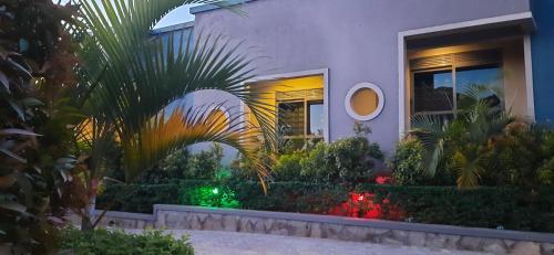 a house with a palm tree in front of it at Ashleys Hotel in Kampala