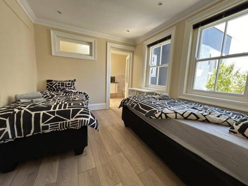 a bedroom with two beds and two windows at The Yellow House in Cape Town