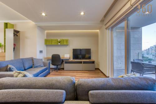 un salon avec deux canapés bleus et une télévision dans l'établissement Luxury 3BR home in St Julians with private terrace by 360 Estates, à Taʼ Ċikkun