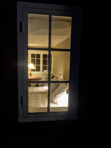 a window with a view of a bed and a lamp at Pensionat Næsgaarden in Allinge