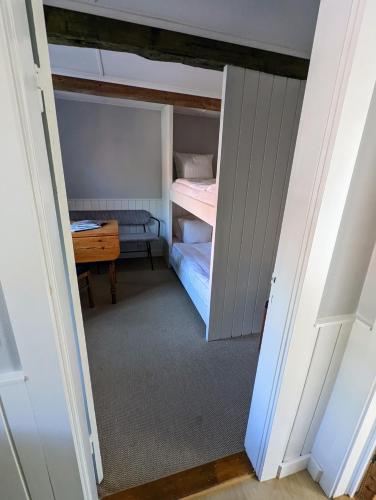 a small room with a bunk bed and a desk at Pensionat Næsgaarden in Allinge