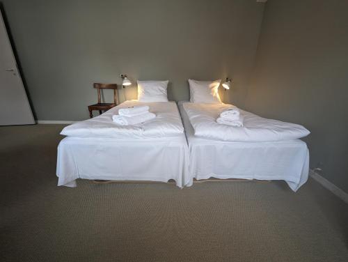 two beds in a room with white sheets and towels at Pensionat Næsgaarden in Allinge