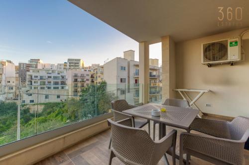 a balcony with a table and chairs and a large window at Luxury 3BR home in St Julians with private terrace by 360 Estates in Taʼ Ċikkun