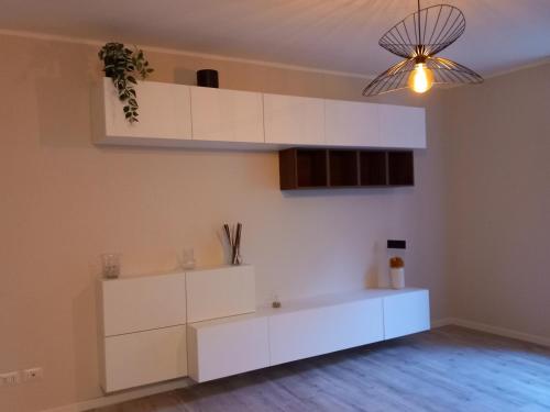a kitchen with white cabinets and a light fixture at La casa di Tina - Civenna in Civenna