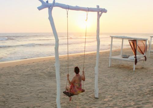 a woman on a swing on the beach at Puerto Bianco Private Residence Collection in Copala