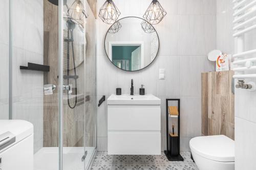 a bathroom with a sink and a toilet and a mirror at Apartament z Garażem! Kołobrzeg -Rybacka przy Ścieżce Rowerowej in Kołobrzeg