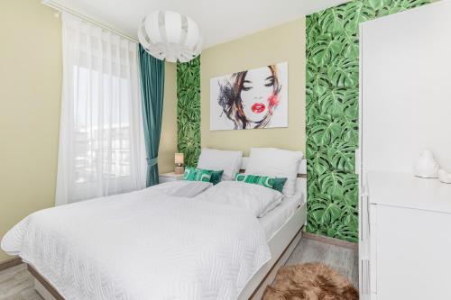 a bedroom with a white bed with a green accent wall at Apartament z Garażem! Kołobrzeg -Rybacka przy Ścieżce Rowerowej in Kołobrzeg