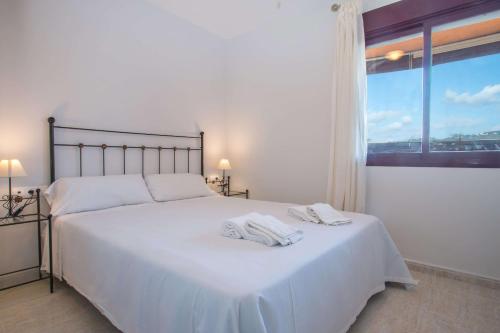 Un dormitorio con una cama blanca con toallas. en Apartamento Coral Beach - PlusHolidays, en Calpe