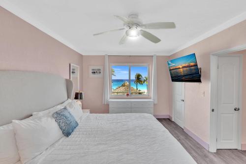 a bedroom with a bed with a ceiling fan and a window at Walkabout 5 Retro Hotel on the beach with live music and a bar in Hollywood