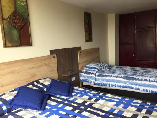 2 letti in una camera con lenzuola bianche e blu di Apartamento completo en el centro de Ipiales a Ipiales