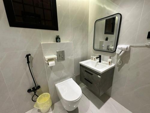 uma casa de banho com um WC, um lavatório e um espelho. em شقة فاخرة غرفتين نوم ودخول ذاتي em Riade