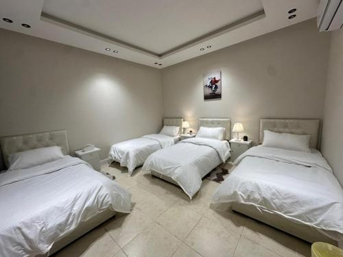 três camas num quarto com lençóis brancos em شقة فاخرة غرفتين نوم ودخول ذاتي em Riade