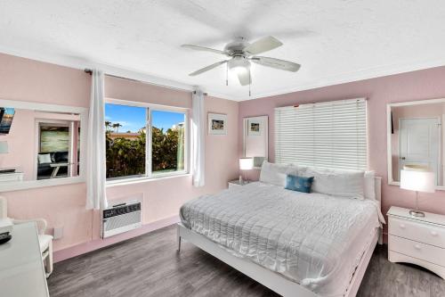 a bedroom with a bed with a ceiling fan and windows at Walkabout 7 Historic Hotel on the beach Live music and bar in Hollywood