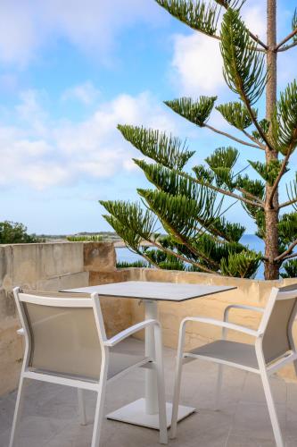 a table and two chairs on a patio with a palm tree at XVI Suites - Adults Only in Naxxar