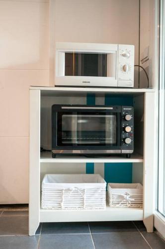 un four micro-ondes dans une armoire blanche dans une cuisine dans l'établissement Appartement le JuTiNi, à Caunes-Minervois