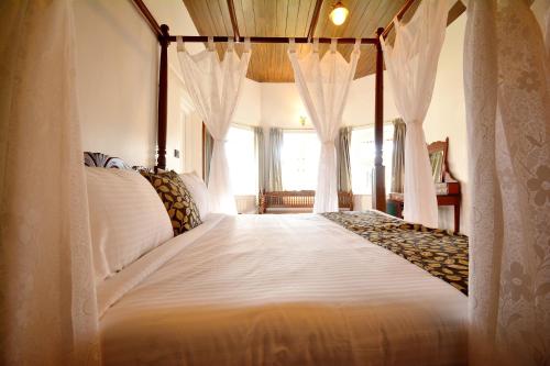a bedroom with a canopy bed with white curtains at Craigmore By Kodai Resort Hotel in Kodaikānāl