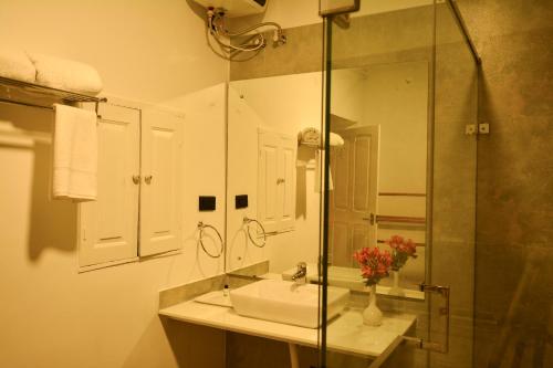 ein Bad mit einem Waschbecken und einer Glasdusche in der Unterkunft Craigmore By Kodai Resort Hotel in Kodaikanal