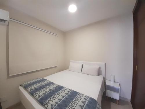 1 dormitorio con cama blanca y manta azul en EXCELENTE Flat junto aos Shoppings JK e Vila Olimpia, en São Paulo