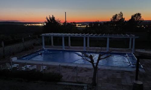 a swimming pool with a pavilion at sunset at Casa en el corazón de Córdoba in Montoro