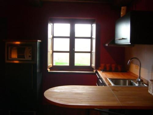 uma cozinha com uma mesa de madeira em frente a uma janela em Apartamento Rural La Aldea Perdida .VV 1434-AS em Pola de Laviana
